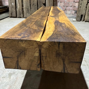 Op de afbeelding: Twee grote stukken gerecycled hout, samengevoegd tot een lange, rechthoekige bank. Het hout heeft een rijke bruine kleur met een natuurlijke, rustieke afwerking. De houtnerf is zichtbaar en draagt bij aan de algehele esthetiek.