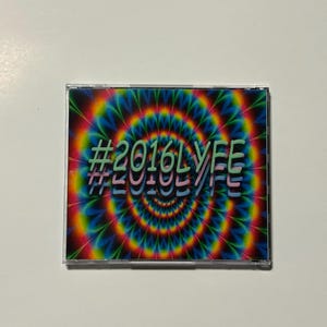 May include: A CD case with a vibrant, psychedelic design. The cover features a swirling pattern of rainbow colors, with the text "#2016LYFE" in a layered, green and pink font. The case is clear, showcasing the artwork.