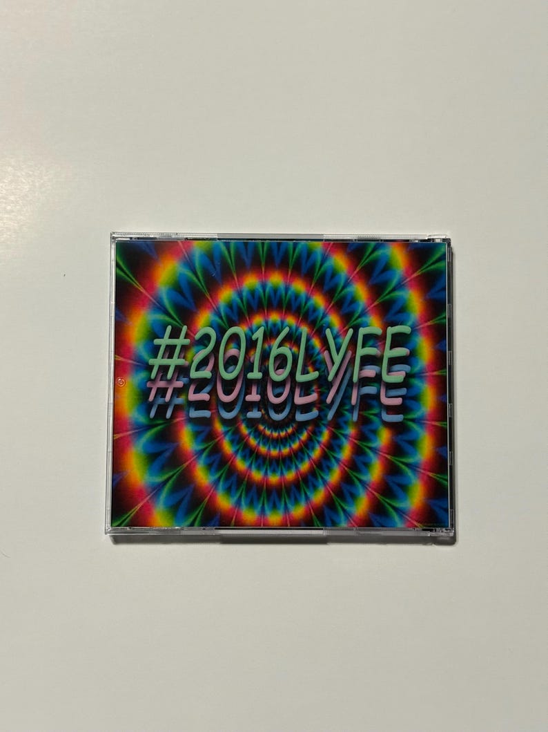 May include: A CD case with a vibrant, psychedelic design. The cover features a swirling pattern of rainbow colors, with the text "#2016LYFE" in a layered, green and pink font. The case is clear, showcasing the artwork.
