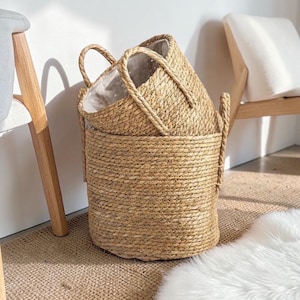 Peut inclure: Trois paniers tressés de différentes tailles, empilés les uns sur les autres. Les paniers sont faits d'une fibre naturelle brun clair et ont des poignées robustes. L'intérieur des paniers est doublé d'un tissu blanc. Les paniers sont adaptés au rangement.