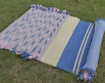 May include: A rolled up blue, pink, and cream striped rug with fringe on the ends.