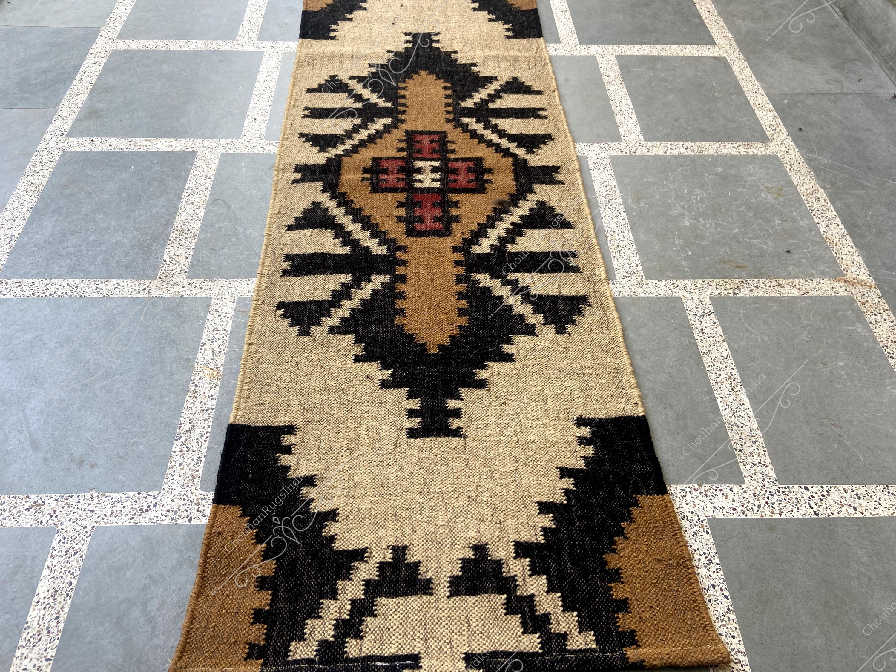 May include: A brown and black patterned rug with a geometric design. The rug is made of natural fibres and has a rustic look.