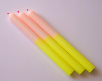 Könnte beinhalten: Drei Ombre-Kerzen mit rosa Oberseite und gelber Unterseite.