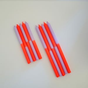 Könnte beinhalten: Ein Set mit zehn Ombre-Geburtstagskerzen. Die Kerzen sind oben helllila und unten in ein leuchtendes Orange übergehend.