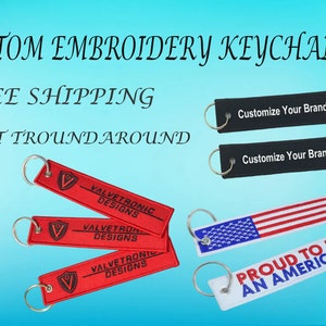 Pode incluir: Uma coleção de chaveiros bordados com diferentes designs. Os chaveiros são vermelhos, pretos, brancos e azuis. Um chaveiro diz "Customize Your Brand Logo". Outro chaveiro diz "Proud to be an American". Um terceiro chaveiro diz "Valvetronic Designs".
