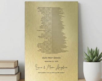May include: A gold-colored metal plaque with engraved song lyrics and the text "OUR FIRST DANCE" and the date "November 12, 2025". Below the text is the names "Lance & Maria Angelica" and the song title "Gloria Estofan "Con Los Años Que Me Quedan".