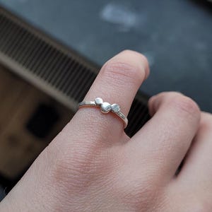 Op de afbeelding: Een zilveren ring met drie kleine, ronde, getextureerde zilveren kralen.