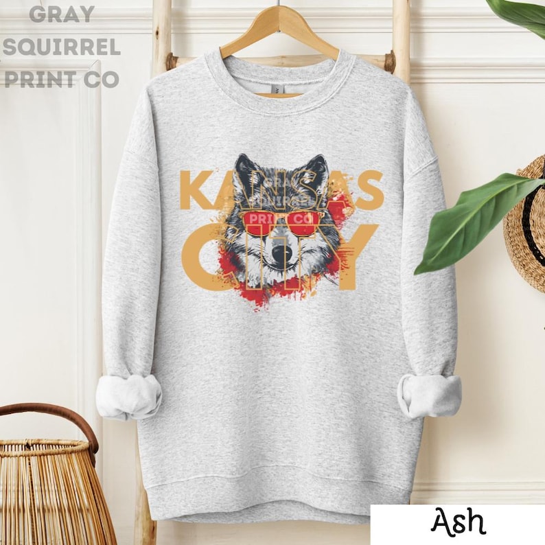 May include: Gray sweatshirt with a wolf wearing red sunglasses and the text "Kansas City" in gold letters.