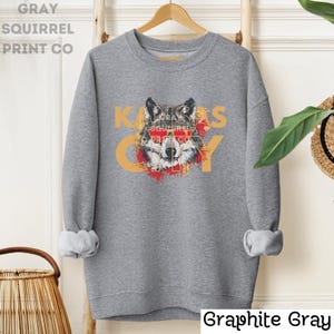 May include: Gray sweatshirt with a wolf wearing sunglasses and the text "Kansas City" in a distressed font.