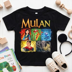 May include: A black short-sleeve t-shirt featuring the word MULAN in large yellow letters above a graphic grid of characters from the film, including Mulan, Mushu, Cri-Kee, Li Shang, and Shan Yu, displayed in colorful square panels.