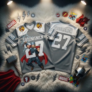 May include: Two grey football-style jerseys with white detailing and the word "Groomsmen" printed on the front. Each jersey has the number "27" in white. One jersey features a Thor graphic. The word "Marvel" is printed on the sleeves.