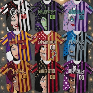 Puede incluir: Nueve camisetas de b&eacute;isbol con villanos de Disney. Cada camiseta tiene la cara de un personaje dividida por la mitad, con el nombre del personaje y el n&uacute;mero "00" en la parte delantera. Las camisetas tienen diferentes combinaciones de colores y patrones.