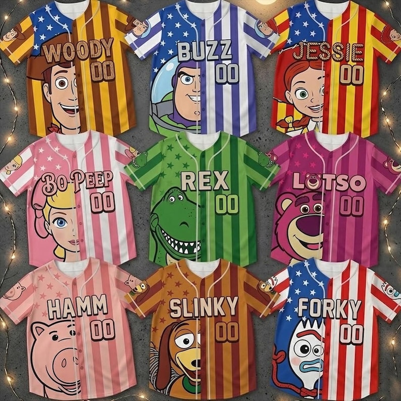 Op de afbeelding: Negen honkbalshirts met personages uit Toy Story. Elk shirt toont het gezicht van een personage aan &eacute;&eacute;n kant, met de naam van het personage en het nummer "00" aan de andere kant. De kleuren zijn onder meer blauw, rood, geel, roze en groen.