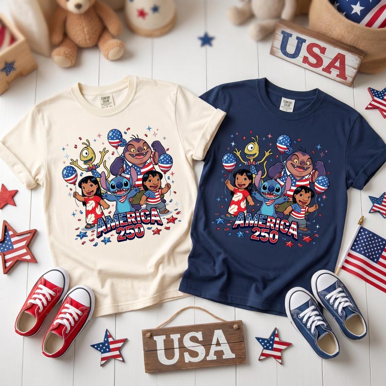 May include: Two short-sleeve t-shirts, one cream and one navy blue, each featuring a graphic of Lilo, Stitch, and other characters holding American flag balloons. The text "AMERICA 250" is printed below the characters. The shirts are surrounded by small American flag stars and two wooden signs labeled "USA".