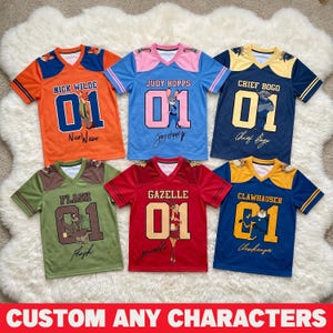 Pu&ograve; includere: Una collezione di maglie a maniche corte colorate con vari personaggi. Ogni maglia ha il nome di un personaggio, il numero 01 e una firma. Le maglie sono arancioni, blu, verdi, rosse e blu navy. Il testo "CUSTOM ANY CHARACTERS" &egrave; in basso.