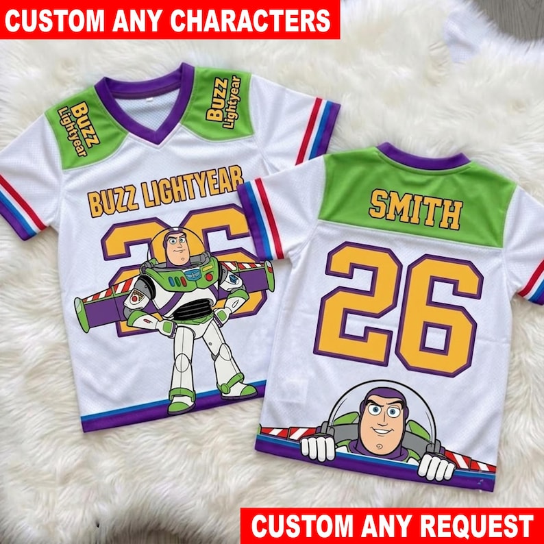 May include: Two white V-neck jerseys featuring Buzz Lightyear graphics. One jersey displays the name Buzz Lightyear and the number 26, while the other shows the name Smith and the number 26. Both shirts have green shoulder panels and striped sleeves.