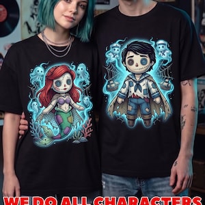 May include: Two black t-shirts featuring graphic illustrations of stitched doll characters. The left shirt displays a mermaid doll with red hair and a green tail, while the right shirt shows a sailor doll with a cape, both surrounded by glowing blue ghosts.