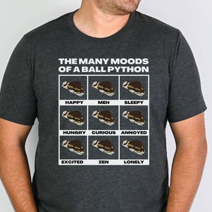 May include: A dark grey heather t-shirt with a white graphic of a ball python in different moods. The text "THE MANY MOODS OF A BALL PYTHON" is above the graphic. The moods include happy, meh, sleepy, hungry, curious, annoyed, excited, zen, and lonely.