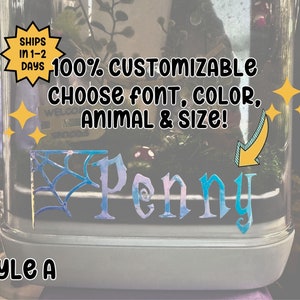 May include: A glass terrarium with a spiderweb design and the name "Penny" written in blue and pink lettering. The terrarium is 100% customizable with a choice of font, color, animal, and size.