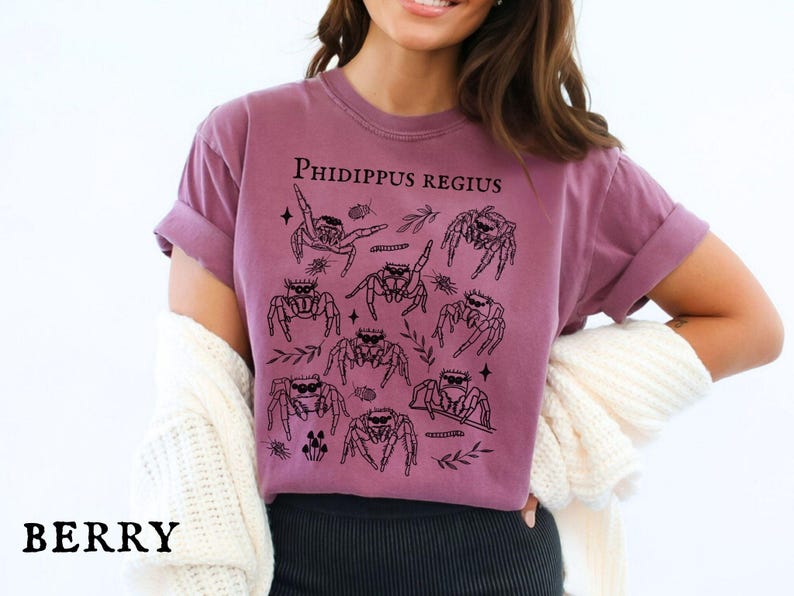 Pu&ograve; includere: T-shirt color bacca con grafica nera di ragni saltatori e la scritta "Phidippus Regius". La maglietta ha maniche corte e una vestibilit&agrave; rilassata. La parola "BERRY" &egrave; stampata in basso.