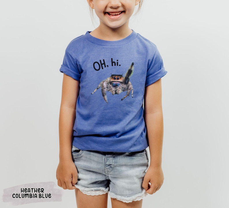 May include: A blue t-shirt with a jumping spider graphic and the text "OH. hi." printed on the front. The shirt is made of a soft, comfortable material and is perfect for everyday wear.