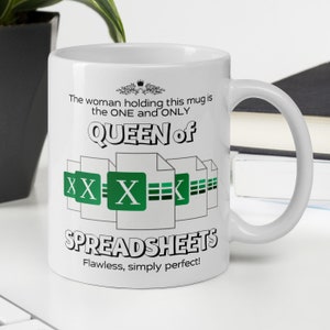 Könnte beinhalten: Weiße Keramiktasse mit grünem und schwarzem Design. Die Tasse zeigt den Text "The woman holding this mug is the ONE and ONLY QUEEN of SPREADSHEETS Flawless, simply perfect!" und eine Grafik mit mehreren Tabellenkalkulationssymbolen.