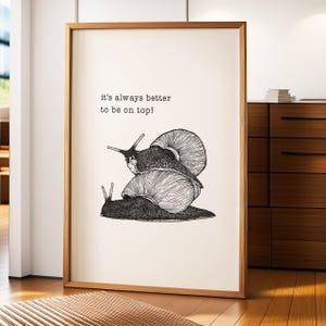 May include: Black and white illustration of three snails stacked on top of each other. The text "it's always better to be on top!" is printed above the snails.