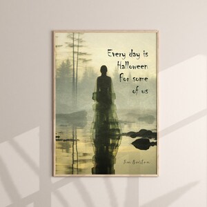 May include: A framed print with a quote by Tim Burton: "Every day is Halloween for some of us". The print features a silhouette of a person standing in a misty forest with a reflection in the water.