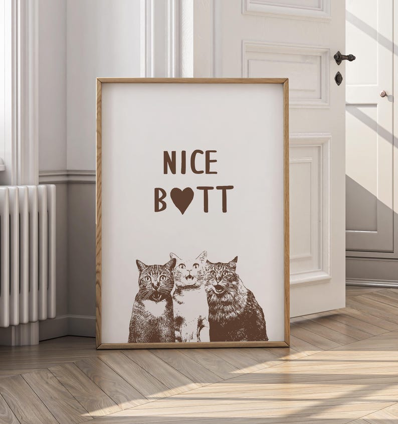 May include: A brown framed print with the text "NICE B❤TT" and a picture of three cats looking at the camera.