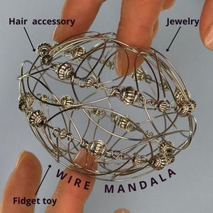 Può includere: Un giocattolo fidget a forma di mandala in filo d'argento con perline decorative. Può essere utilizzato come accessorio per capelli o come gioiello.