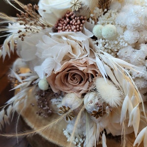 May include: A dried flower arrangement in a rustic style with white, beige, and brown tones. The arrangement features dried roses, pampas grass, and other dried flowers.