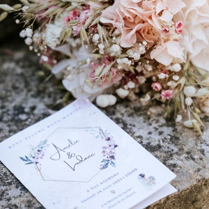 May include: A white wedding invitation with a gold geometric frame and floral accents. The invitation reads "Aurelie & Ludovic" and includes the date "Samedi 24 Juin 2023 | 15h00".
