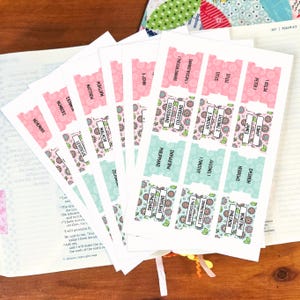 May include: A set of adhesive Bible index tabs printed on white sheets. The tabs feature floral patterns in shades of pink, green, and blue, with black text identifying various books of the Bible such as Nehemiah, Matthew, Malachi, and Ephesians.