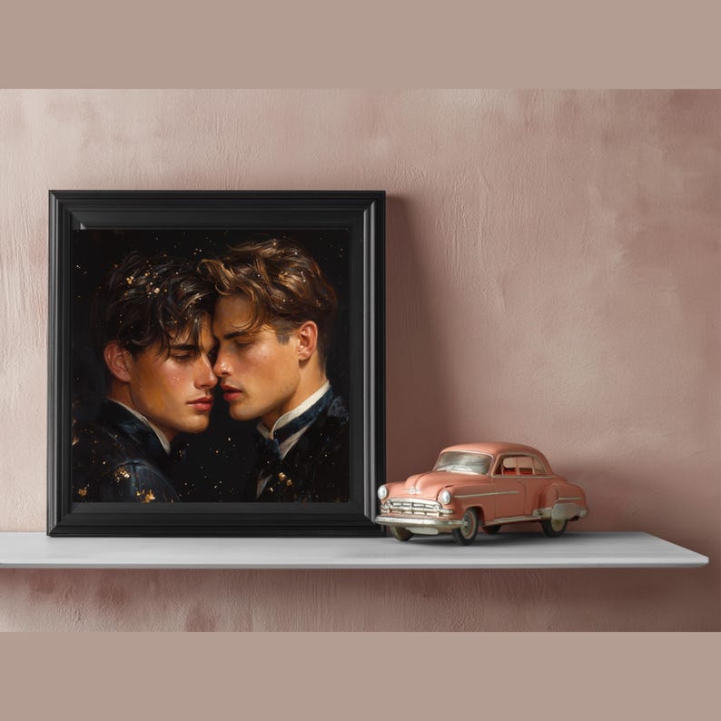 May include: A framed square print featuring two individuals with dark hair facing each other in a dark setting with gold flecks, positioned next to a small, vintage-style pink toy car. The artwork is encased in a simple black frame.
