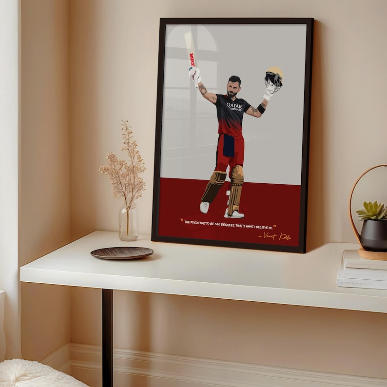 May include: Framed art print featuring a stylized illustration of a cricket player in a black and red uniform, holding a bat and helmet. The artwork has a red and gray background with a quote at the bottom.