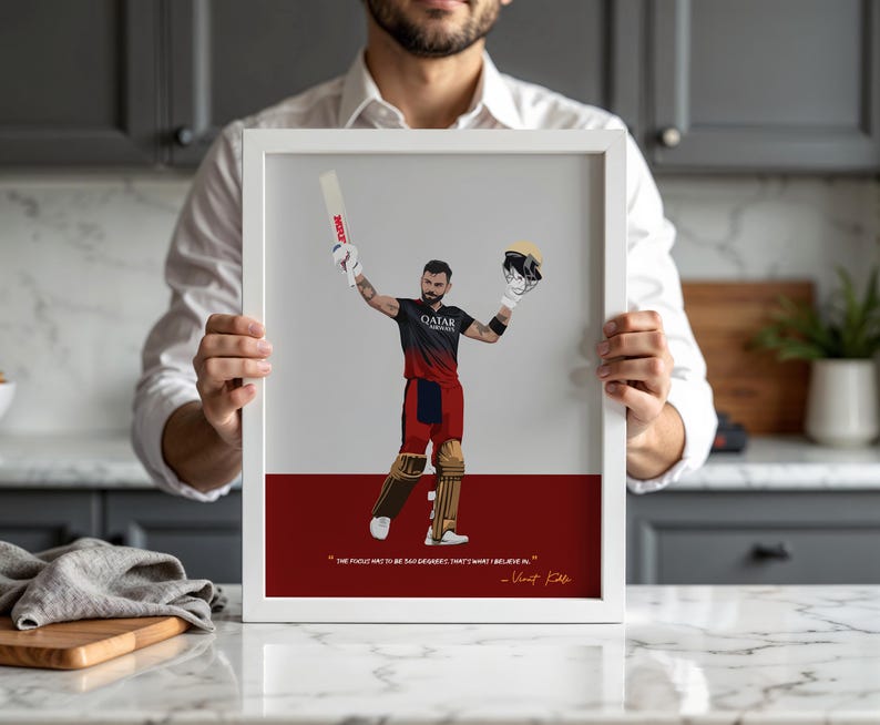 May include: A framed print featuring a stylized illustration of a cricket player in a black and red uniform, holding a bat and helmet. The print includes a quote by Virat Kohli and is set against a white and red background.