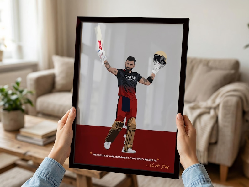 May include: Framed art print featuring a stylized illustration of a cricket player in a red and black uniform, holding a bat and helmet. The print has a white and red background with a quote by Virat Kohli. The frame is dark brown.