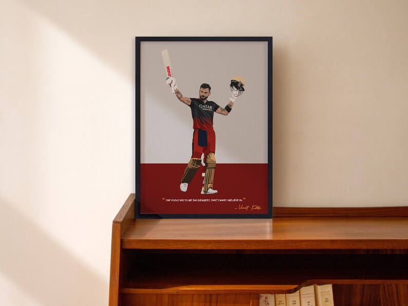 May include: A framed art print featuring a cricket player in a red and black uniform, holding a bat and helmet. The artwork has a minimalist style with a red and gray background. The print includes a quote and signature.