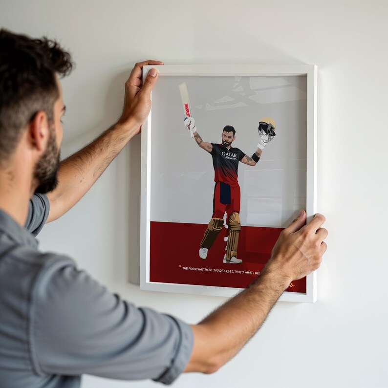 May include: Framed artwork featuring a cricket player in a black and red uniform, holding a bat and helmet. The artwork has a white frame and a red and gray background. Text at the bottom reads, "...the focus has to be so intense that's what I like."