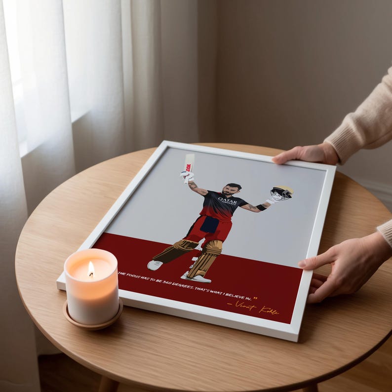May include: A framed print featuring a cricket player in a red and black uniform, holding a bat and helmet, with the text "THE FOCUS HAS TO BE 360 DEGREES. THAT'S WHAT I BELIEVE IN." and the name "Virat Kohli."
