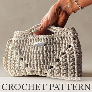 Può includere: Una borsa all'uncinetto beige con manico, tenuta in mano. La borsa ha un aspetto strutturato e intrecciato e una piccola etichetta "handmade". Le parole "CROCHET PATTERN" sono visualizzate sotto.