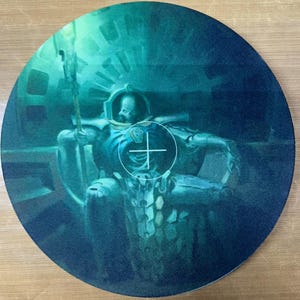 Könnte beinhalten: Rundes, teal-farbenes Mauspad mit einer detaillierten Illustration eines futuristischen Kriegers in Rüstung. Der Krieger ist zentriert, mit einem weißen Fadenkreuz über dem Bild. Der Hintergrund hat einen Farbverlauf, der von Teal zu Dunkelblau übergeht.