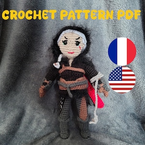 May include: A crocheted doll with black hair, dressed in a black outfit with brown and grey details. The doll has a red mark on its face and holds a red and white fabric. The text "CROCHET PATTERN PDF" is displayed at the top.