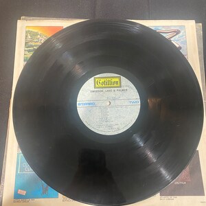 May include: Black vinyl record with a Cotillion Records label. The label features the text "Cotillion", "SD 9040", "Emerson, Lake & Palmer", "Stereo", and "Two".