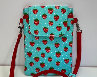 May include: A small blue and white crossbody bag with a red strap. The bag has a strawberry print and white polka dots.