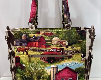 May include: A brown and white tote bag with a red, white, and blue patchwork design. The bag features a farm scene with red barns, horses, and a vintage truck. The bag has two brown straps with gold star accents.