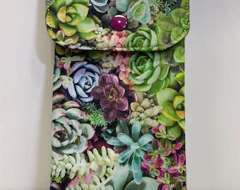 May include: A green fabric pouch with a floral print of succulents. The pouch has a flap with a single purple button closure.