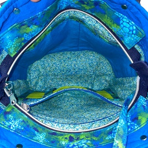 May include: The inside of a blue tote bag with a zipped pocket and a green and blue floral print lining.