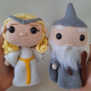 May include: Two crocheted amigurumi dolls, one a female figure with blonde hair and a white dress, the other a male figure with a grey beard and a grey robe and hat.