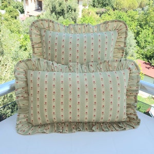 May include: Two green and white striped pillowcases with a small red floral pattern and ruffled edges.